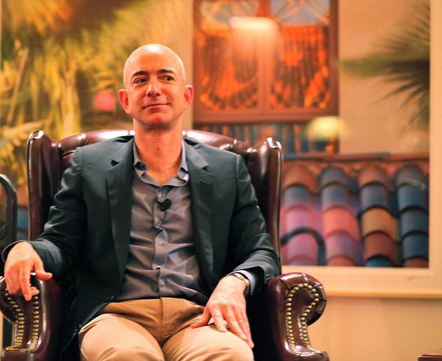 Jeff Bezos sitting in chair with colorful background